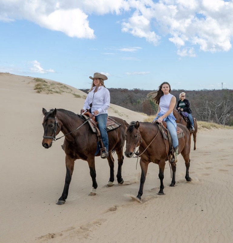 People riding horses on the dunes