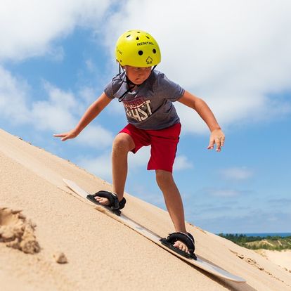Young boy sand boarding at the dunes