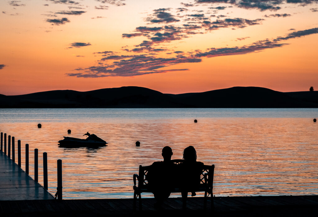 Couple at sunset sitting on bench by the water