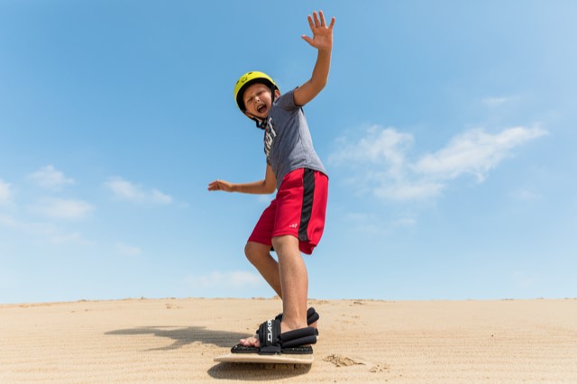 Boy sand boarding on dunes